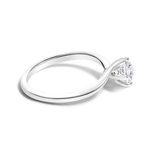 White metal ring with a round white gemstone in a four-prong setting, shot at a slight angle showing the band and setting side.