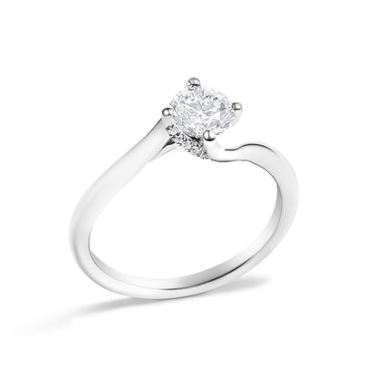 White metal ring with a round center white gemstone in a four-prong setting and surrounding smaller round white gemstones, shown at a slight angle on a white background.