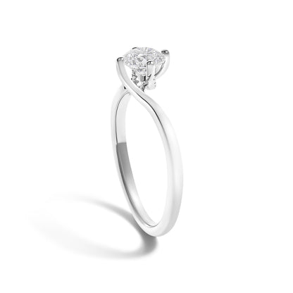 White metal ring with a twisted band design and a single round white gemstone in a four-prong setting, shot at a slight angle against a white background.