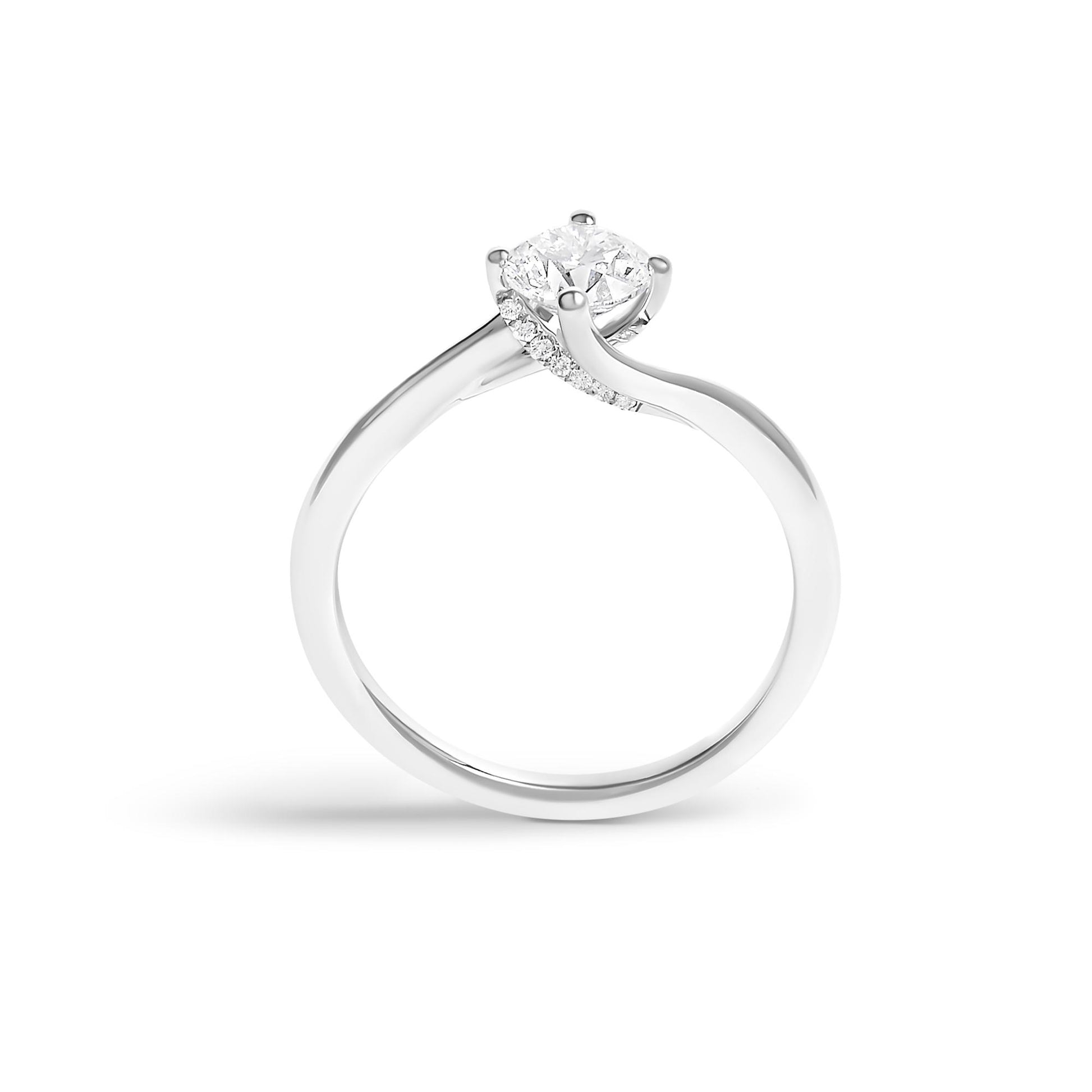 White metal ring viewed from the side, featuring a round white gemstone in a four-prong setting and additional small round white gemstones along the band.