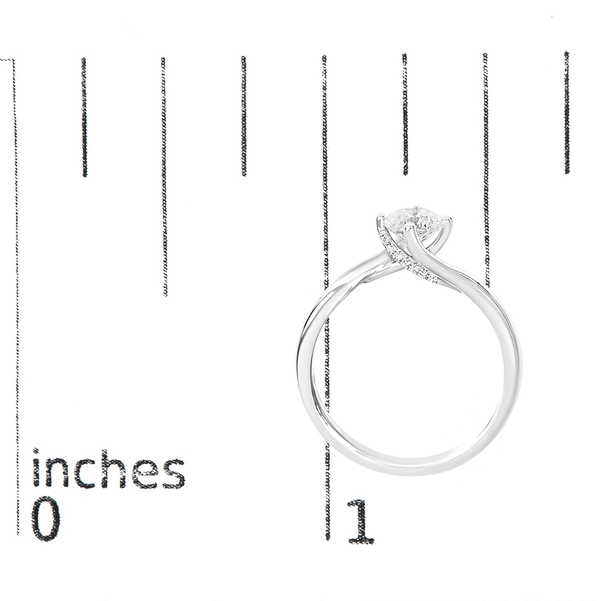 White metal ring with one round white gemstone in a 4-prong setting and multiple smaller round white gemstones in prong settings along the band, shown from a side angle on a ruler for size reference.
