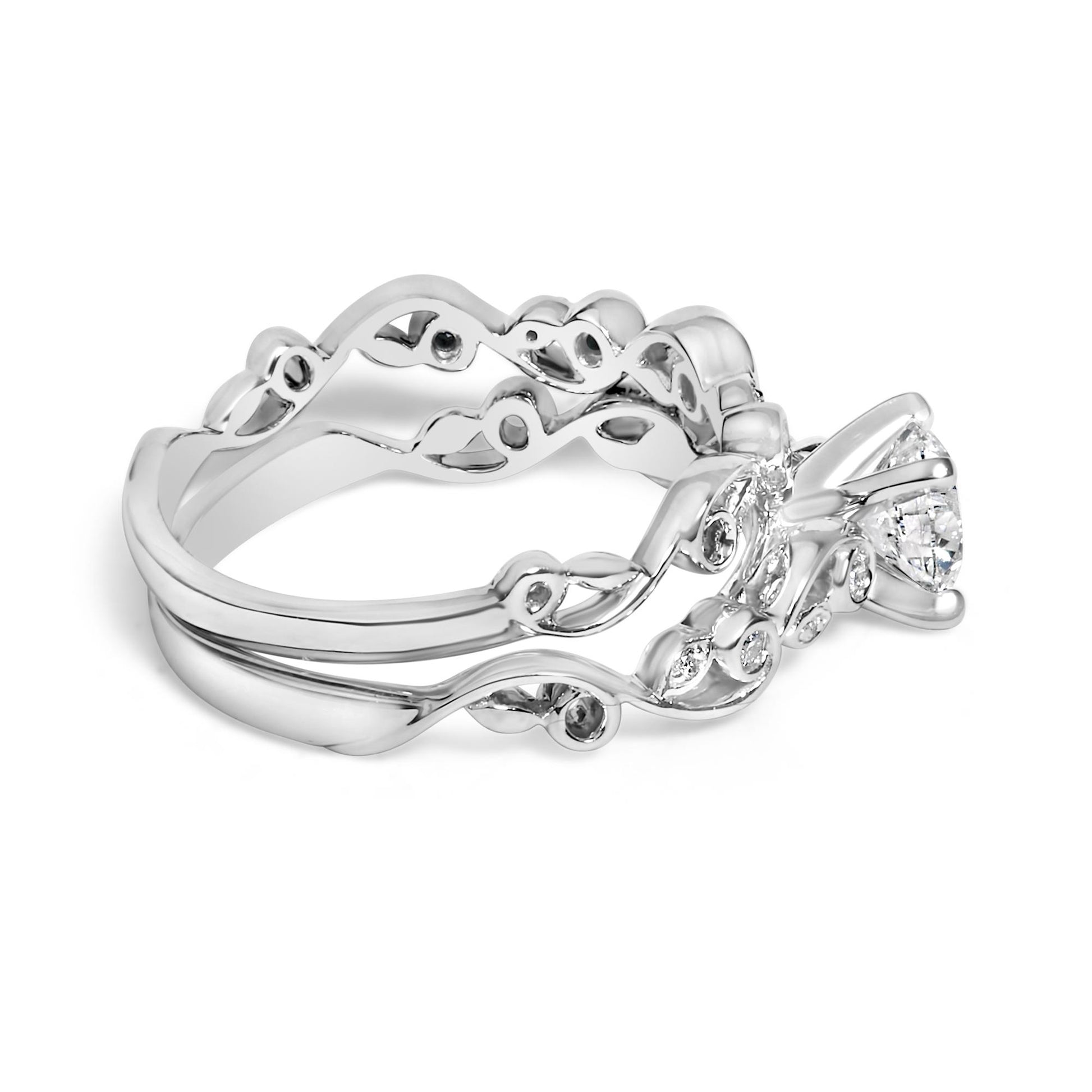Side angle view of a white metal ring set with a large round white gemstone in a prong setting, accompanied by two bands with intricate swirling designs each accented with multiple smaller round white gemstones in prong settings.