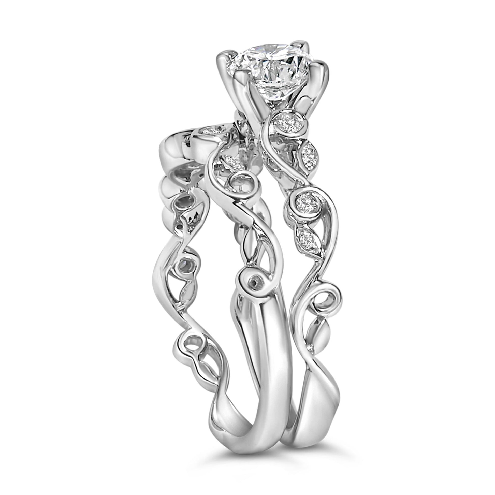 Close-up front angle of two white rings with swirling bands, each adorned with round white gemstones in prong settings.