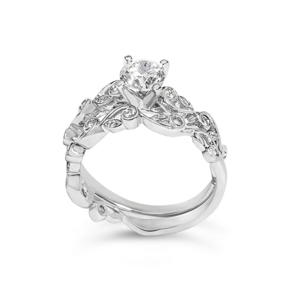 Close-up front angle of a white metal ring with a large round white gemstone in prong setting at the center and smaller round white gemstones set in intricate swirl designs along the band.