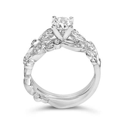 Close-up front angle of a white metal ring with a large round white gemstone in prong setting and smaller round white gemstones set along an intricate band.