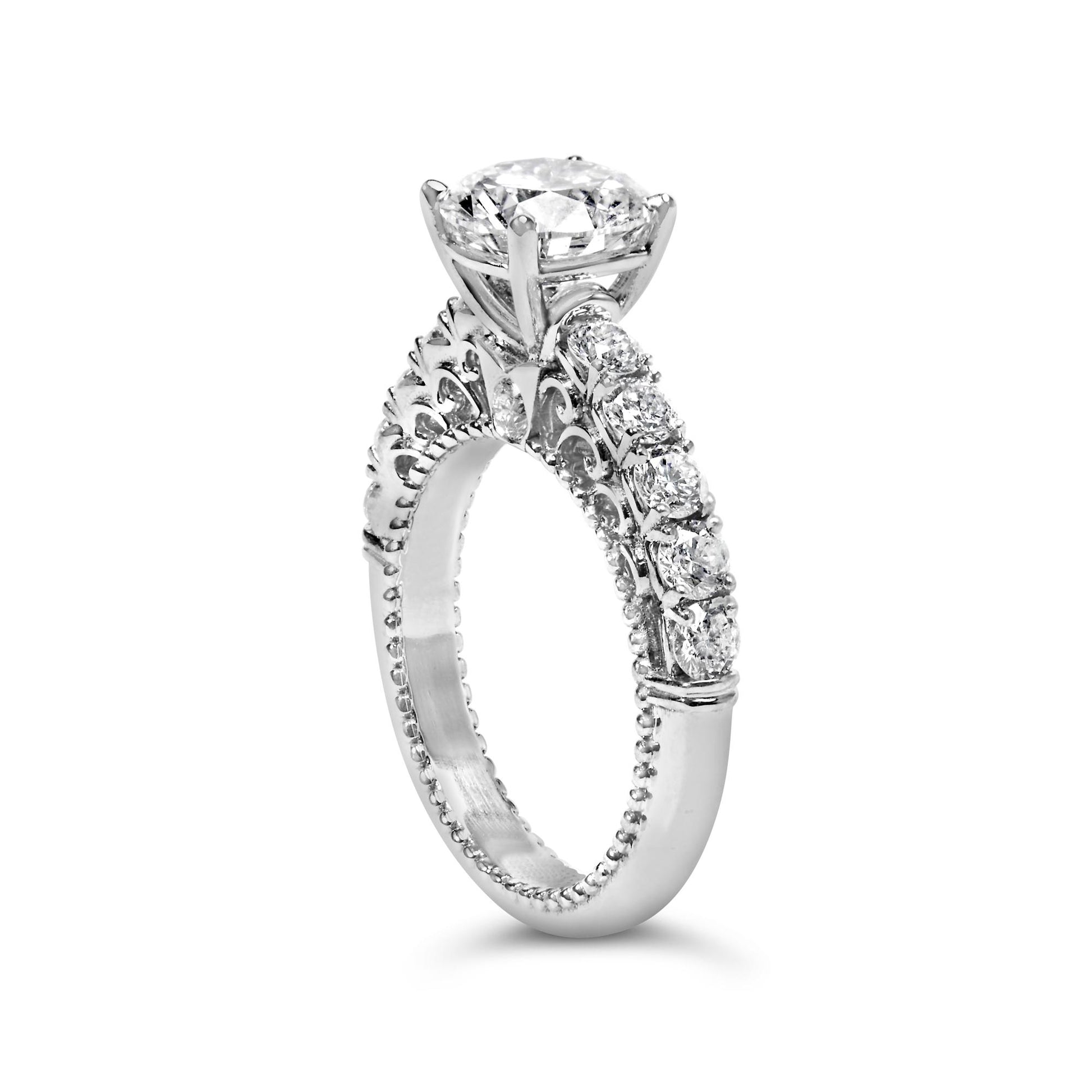 Close-up front angle of a white metal ring featuring one round white gemstone in a prong setting at the center, surrounded by a band decorated with multiple round white gemstones in shared prong settings and intricate design details.