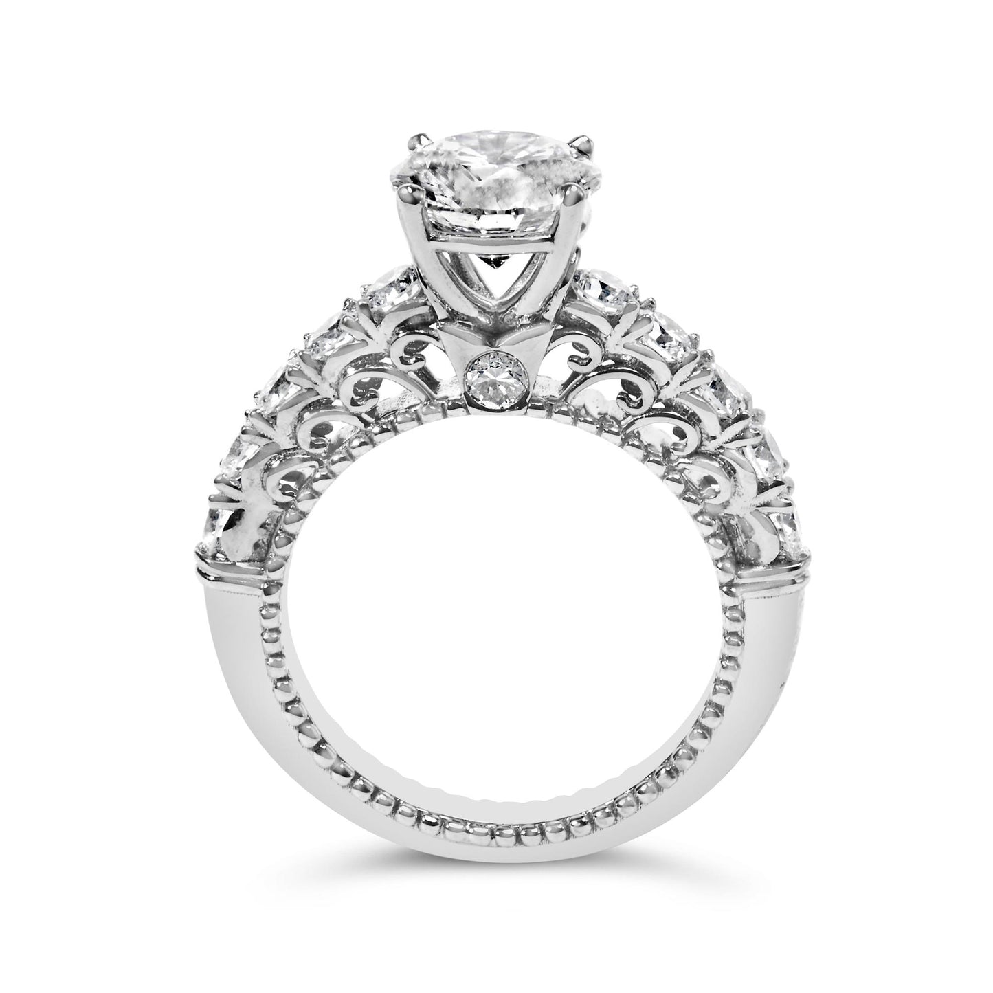 Close-up front angle of a white metal ring featuring one round white gemstone in a prong setting at the center and multiple round white gemstones in shared prong settings around the band with intricate decorative metalwork.