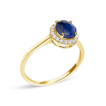 Close-up angled view of a yellow metal ring featuring a round blue gemstone held by four prongs, surrounded by a halo of round white gemstones in shared prong settings.