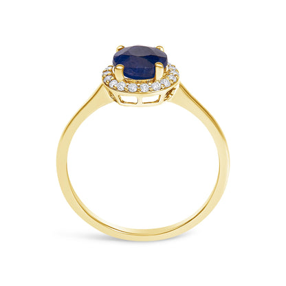 Yellow metal ring with a round blue gemstone in a four-prong setting, surrounded by a circle of small round white gemstones in shared prong settings, shown in a front-facing angle.