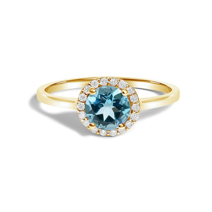 Yellow metal ring with a round blue gemstone in the center surrounded by round white gemstones in a shared prong setting, shown in a front close-up angle.