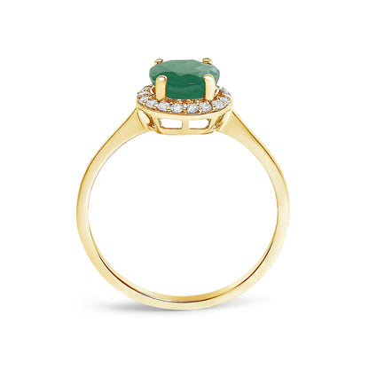 Yellow metal ring shown from the side angle with a green round gemstone in a four-prong setting surrounded by a halo of white round gemstones in a shared prong setting.