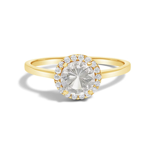 Yellow metal ring with a large round white gemstone in a 4-prong setting, surrounded by smaller round white gemstones in a shared prong setting, front-facing angle on a white background.