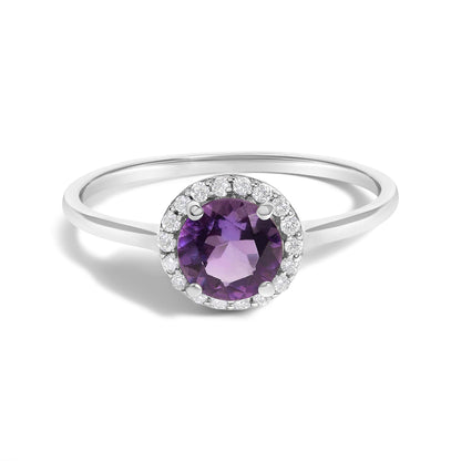 White metal ring with a round purple gemstone in a four-prong setting, surrounded by small white round gemstones in a shared prong setting, shown from a top-front angle on a white background.