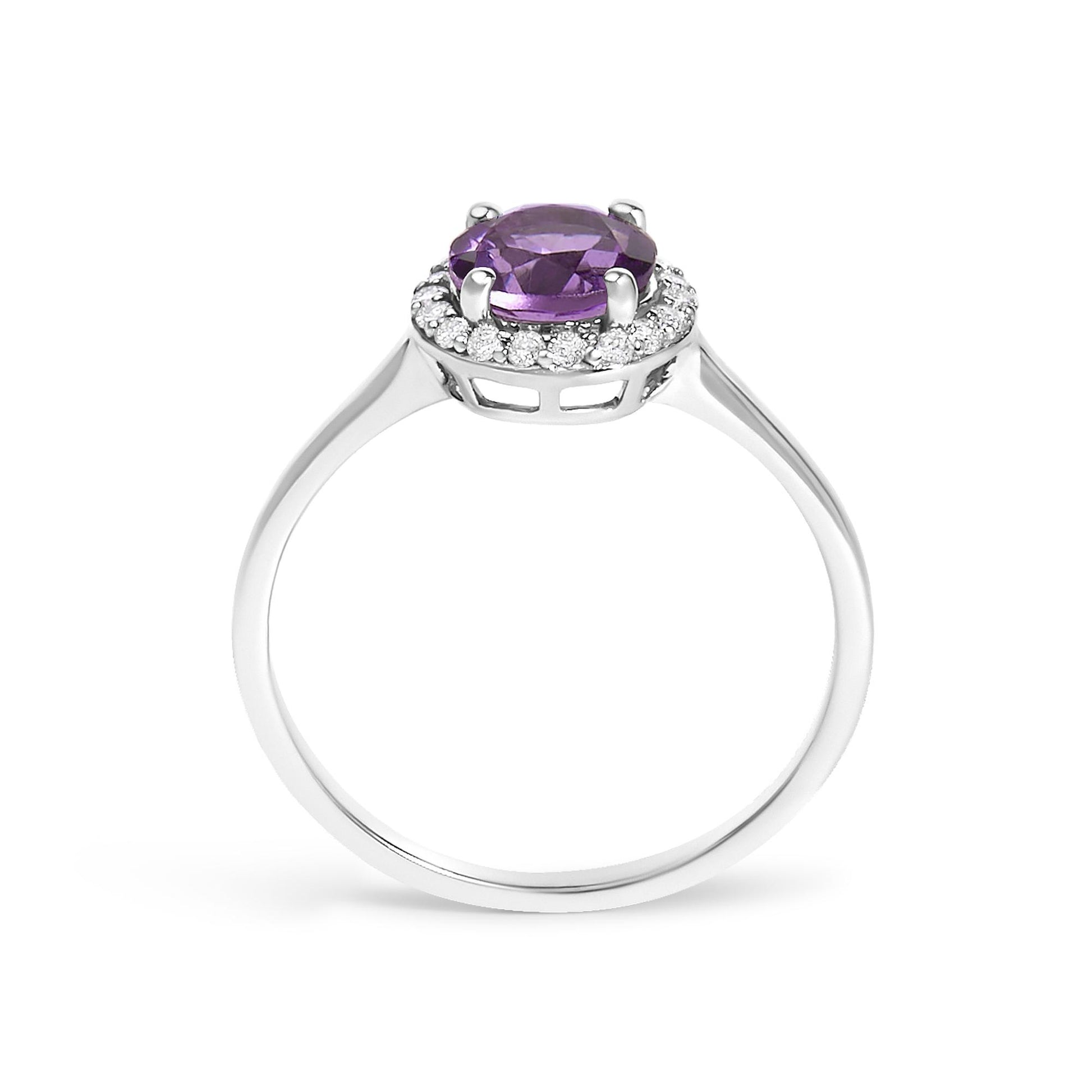 White metal ring shown from the side angle with a round purple gemstone in four-prong setting surrounded by a circle of small round white gemstones in shared prong setting.