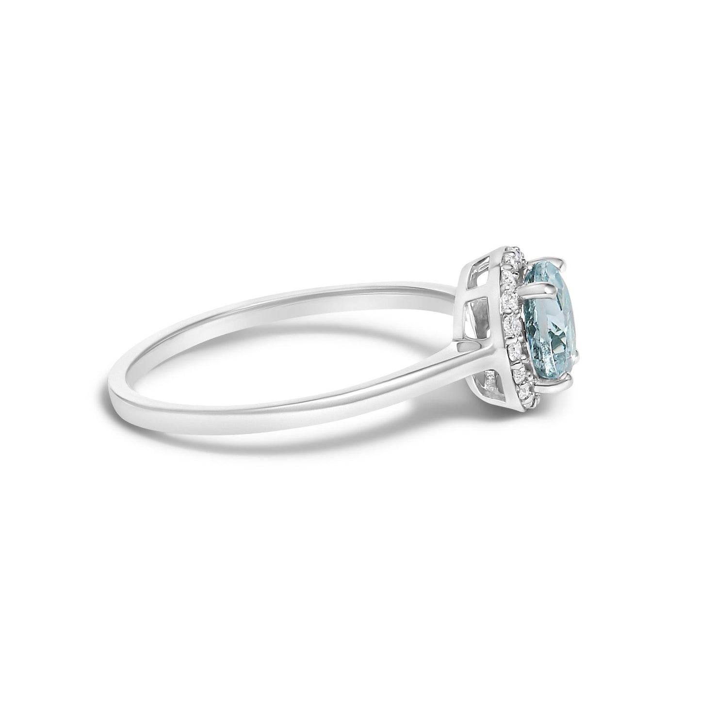 Side view of a white metal ring with a round blue gemstone in a four-prong setting, surrounded by a halo of small round white gemstones in a shared prong setting.