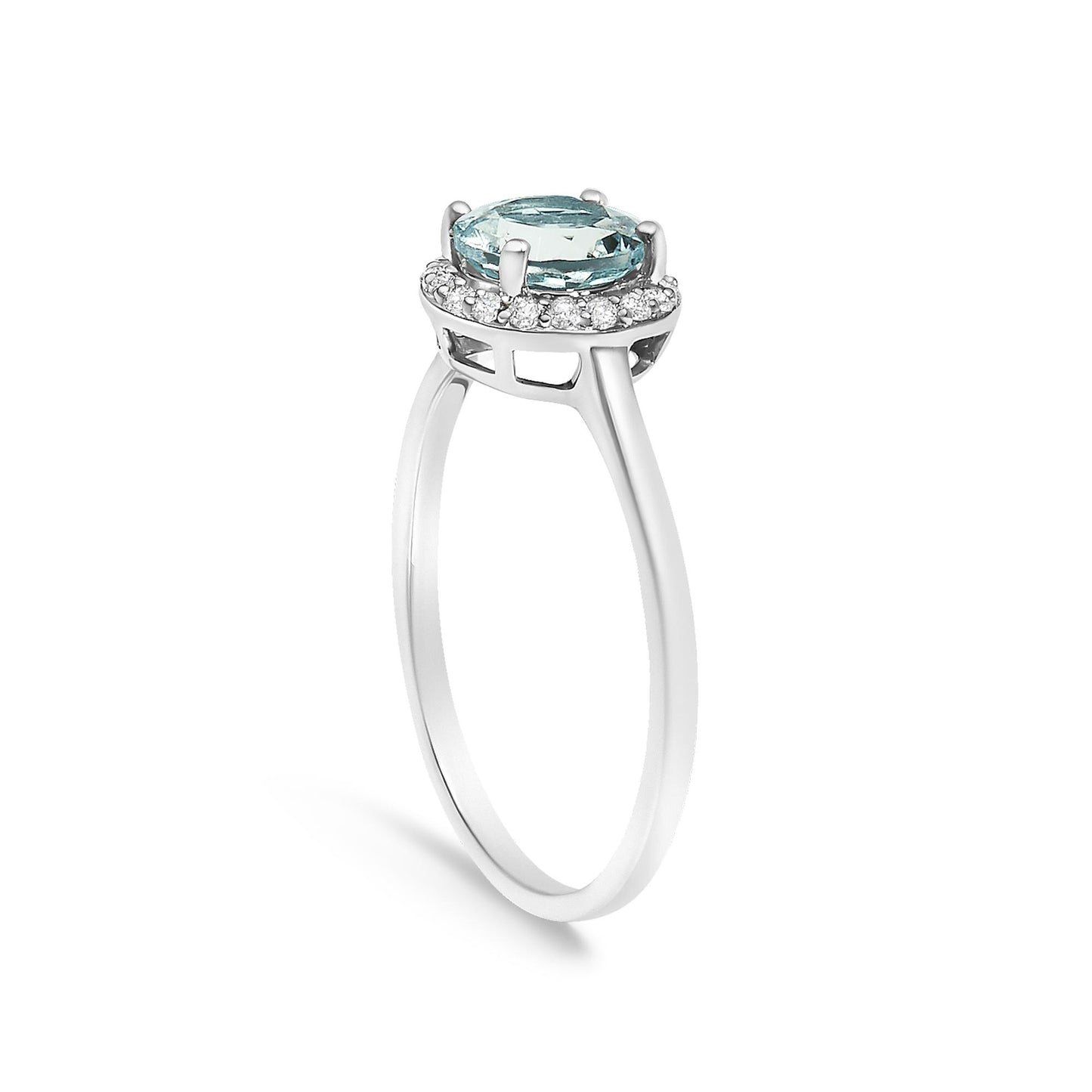 Side angle view of a white metal ring featuring a round blue gemstone in a four-prong setting, surrounded by a halo of round white gemstones in shared prong settings.