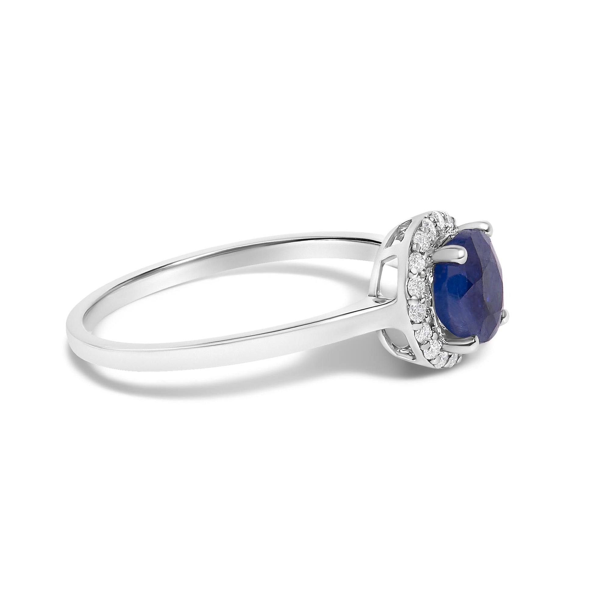 Close-up side angle of a white ring featuring a round blue gemstone in a four-prong setting, surrounded by small round white gemstones in a shared prong setting.