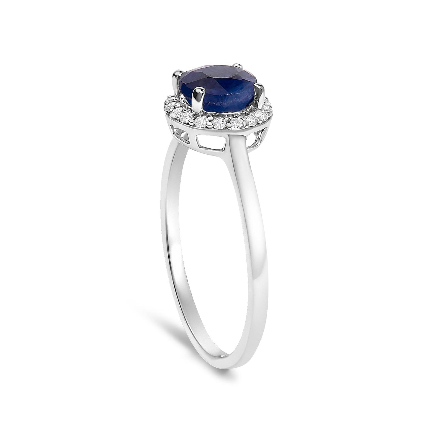 White metal ring with a round blue gemstone center set in four prongs, surrounded by a halo of small round white gemstones in shared prong settings, shown at a slight angle.