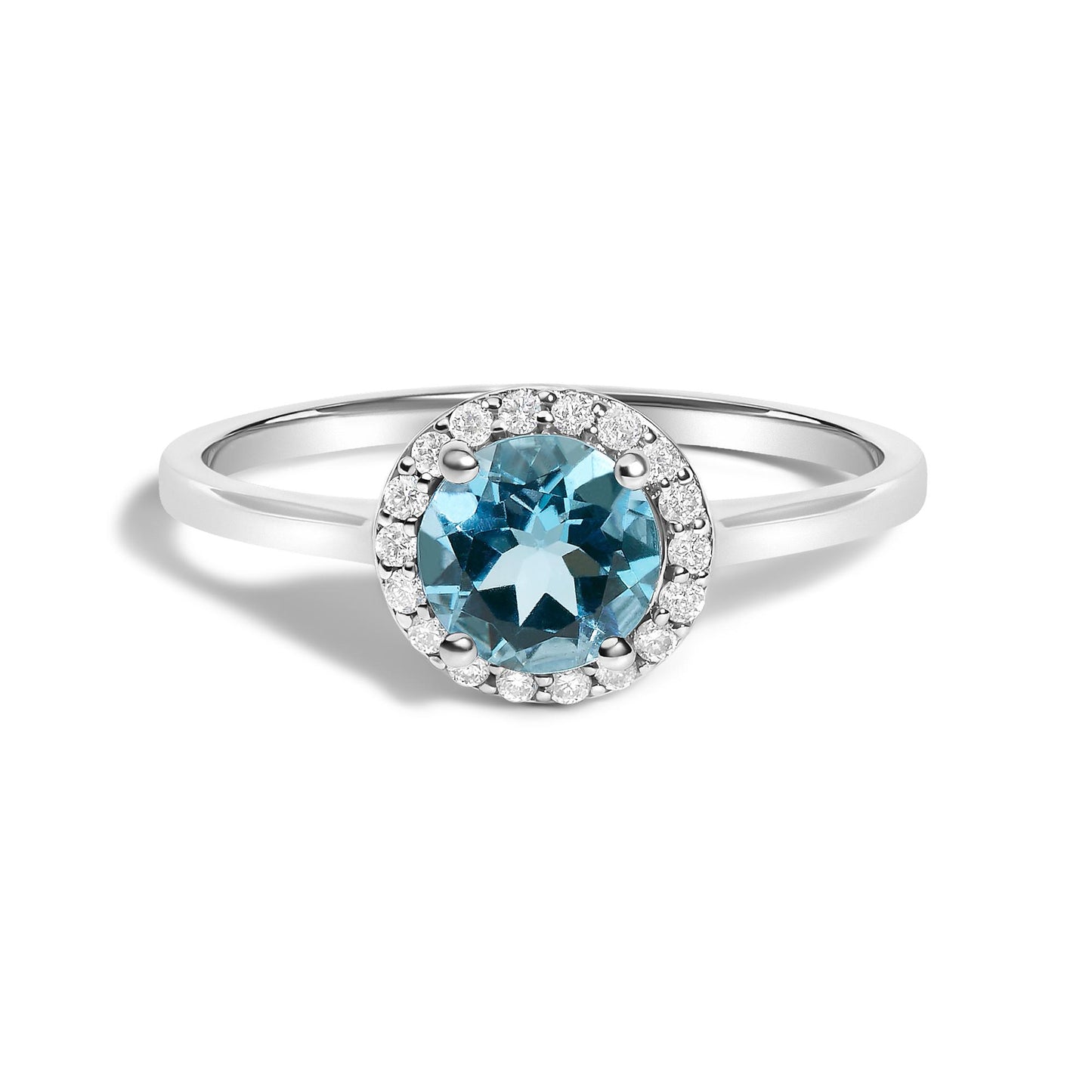 White metal ring with a round blue gemstone center held by four prongs, surrounded by a halo of small round white gemstones in shared prong setting, shown from a front angle on a white background.