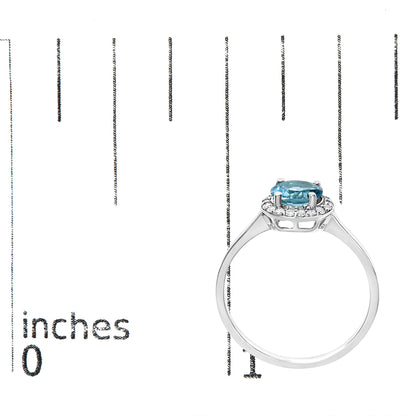 White metal ring with a round blue gemstone at the center surrounded by small round white gemstones in a shared prong setting, shown on a scale from a side angle.