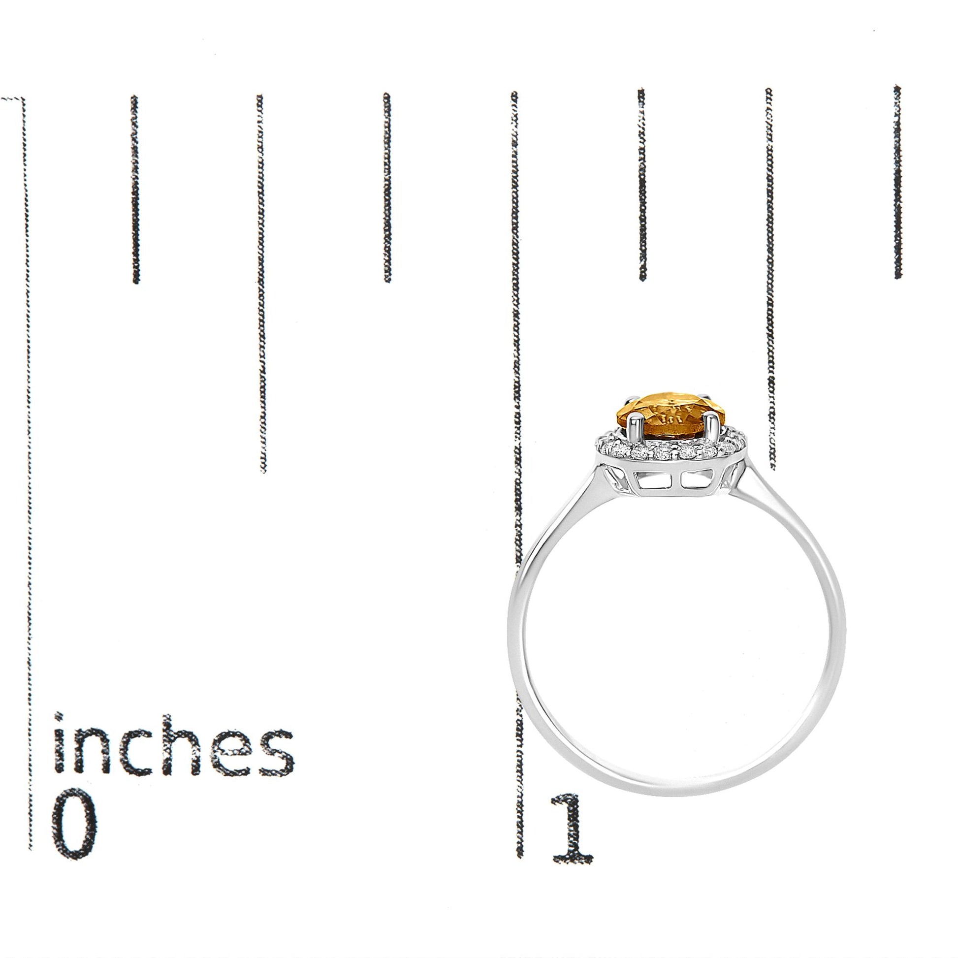 White metal ring shown on a scale from side view, featuring a round orange gemstone set with four prongs and surrounded by a halo of small round white gemstones in shared prong settings.