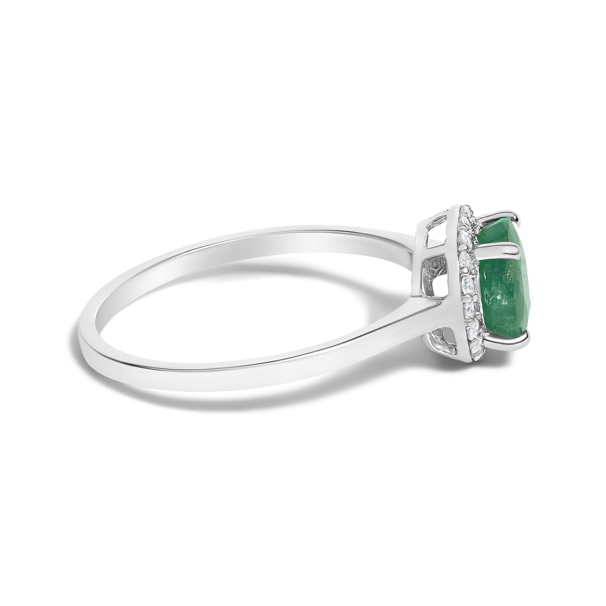 Side view of a white metal ring with a central green gemstone set in a four-prong setting, surrounded by round white gemstones in a shared prong setting.
