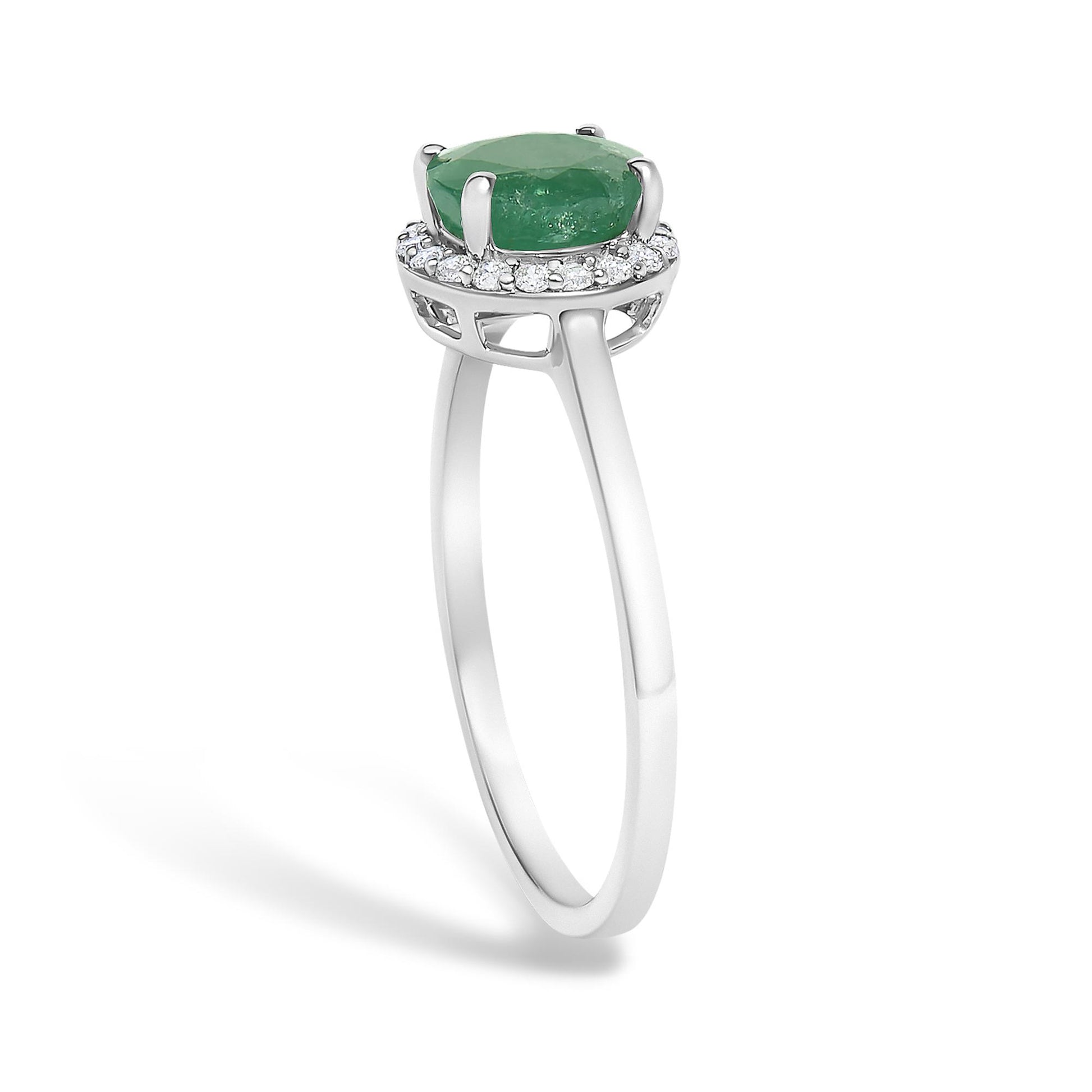 White metal ring shown from a side angle with a round green gemstone in a four-prong setting surrounded by round white gemstones in a shared prong setting.