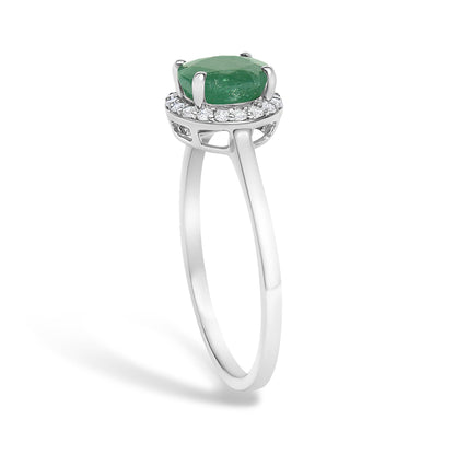 White metal ring shown from a side angle with a round green gemstone in a four-prong setting surrounded by round white gemstones in a shared prong setting.
