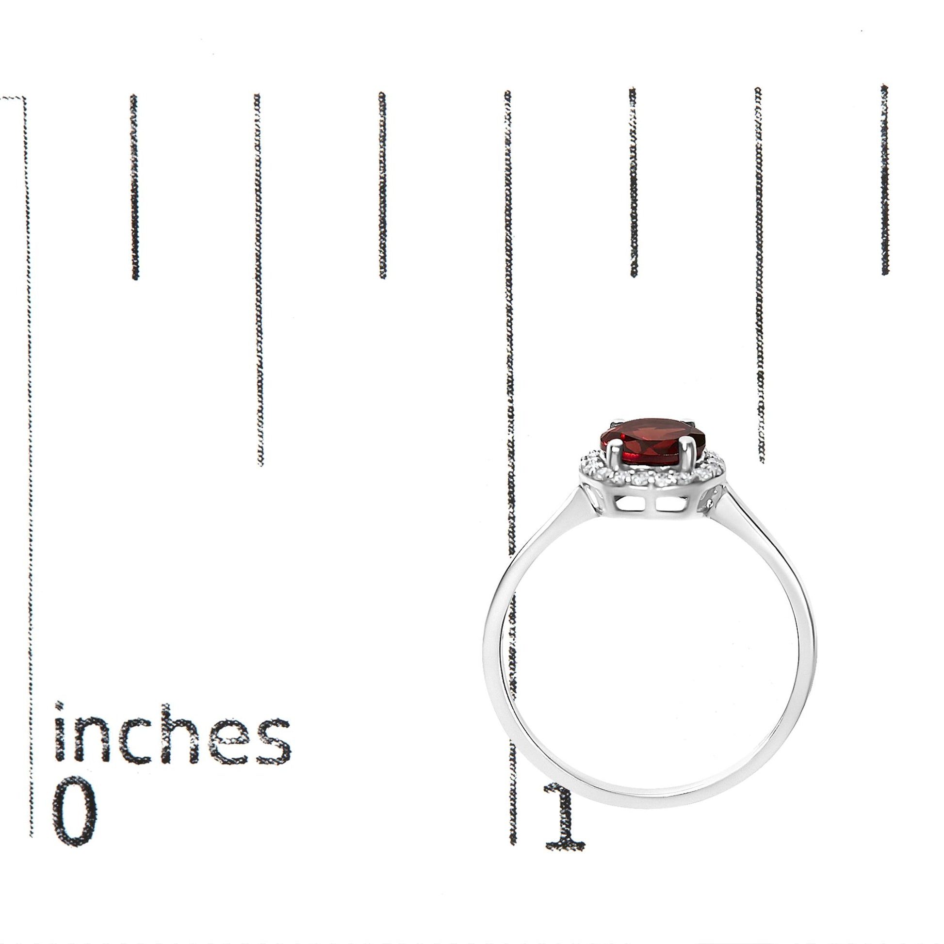 Ring with a white metal band and a round red gemstone in a 4-prong setting, surrounded by multiple small white round gemstones in a shared prong setting; shown on a scale from the side angle.