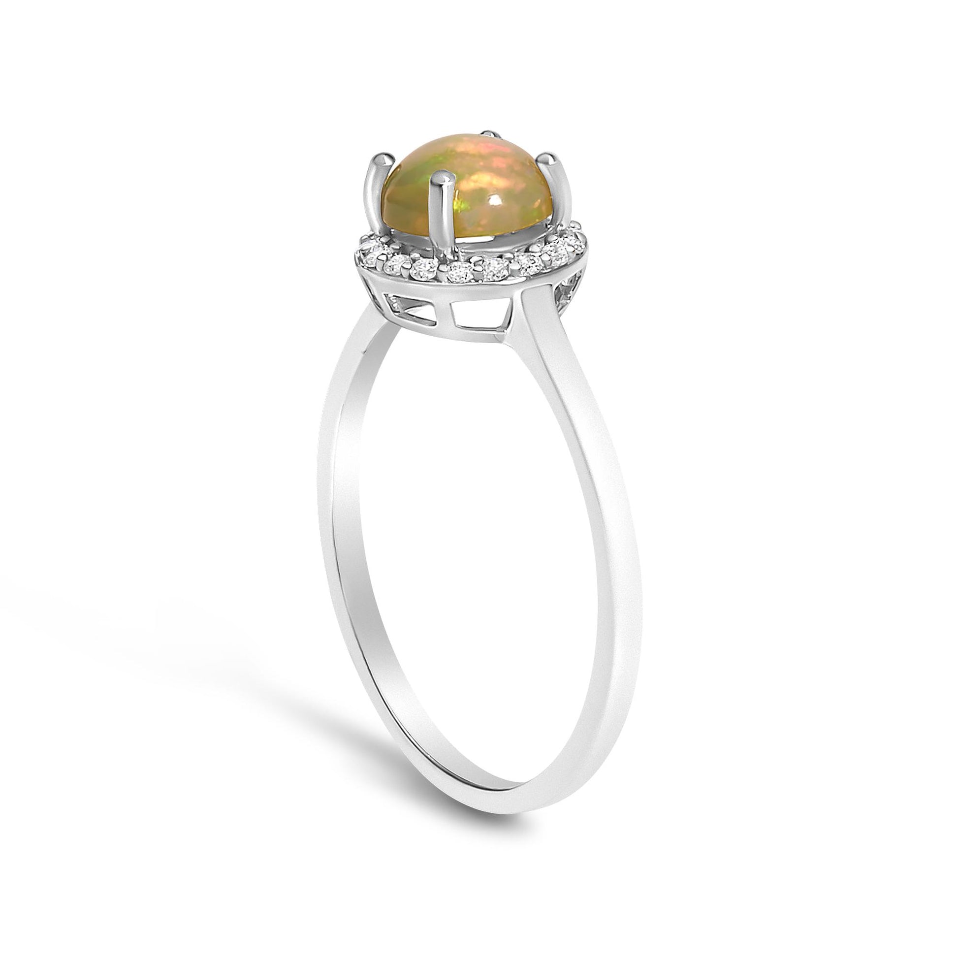 White metal ring with a round multi-color opal gemstone set in four prongs, surrounded by a halo of small round white gemstones in a shared prong setting, side angle view.