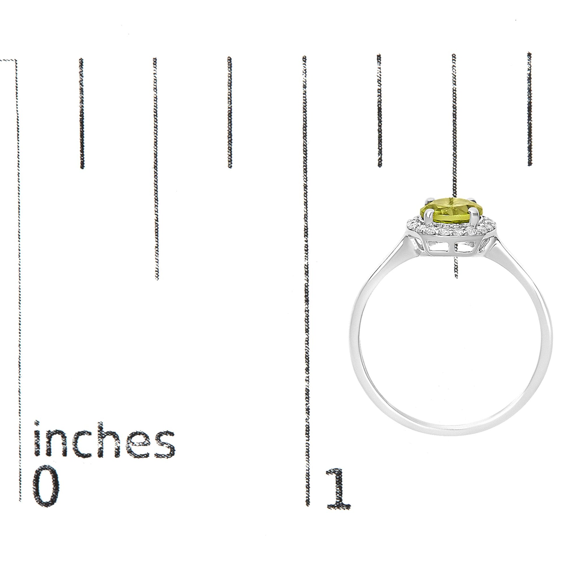 Ring shown on a scale, side view, featuring a white metal band with a round green gemstone held by four prongs at the center, surrounded by small round white gemstones in a shared prong setting.