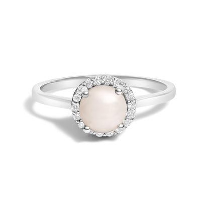 Front angle view of a white metal ring featuring a round pale central gemstone surrounded by a halo of small white round gemstones in shared prong setting.