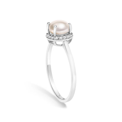 White metal ring shown from a side angle with a central rounded smooth pale gemstone held by four prongs, surrounded by a halo of small white round gemstones in a shared prong setting.