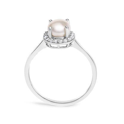 Close-up front angle of a white metal ring featuring a central round pearl held by four prongs, surrounded by a halo of small round white gemstones in a shared prong setting.