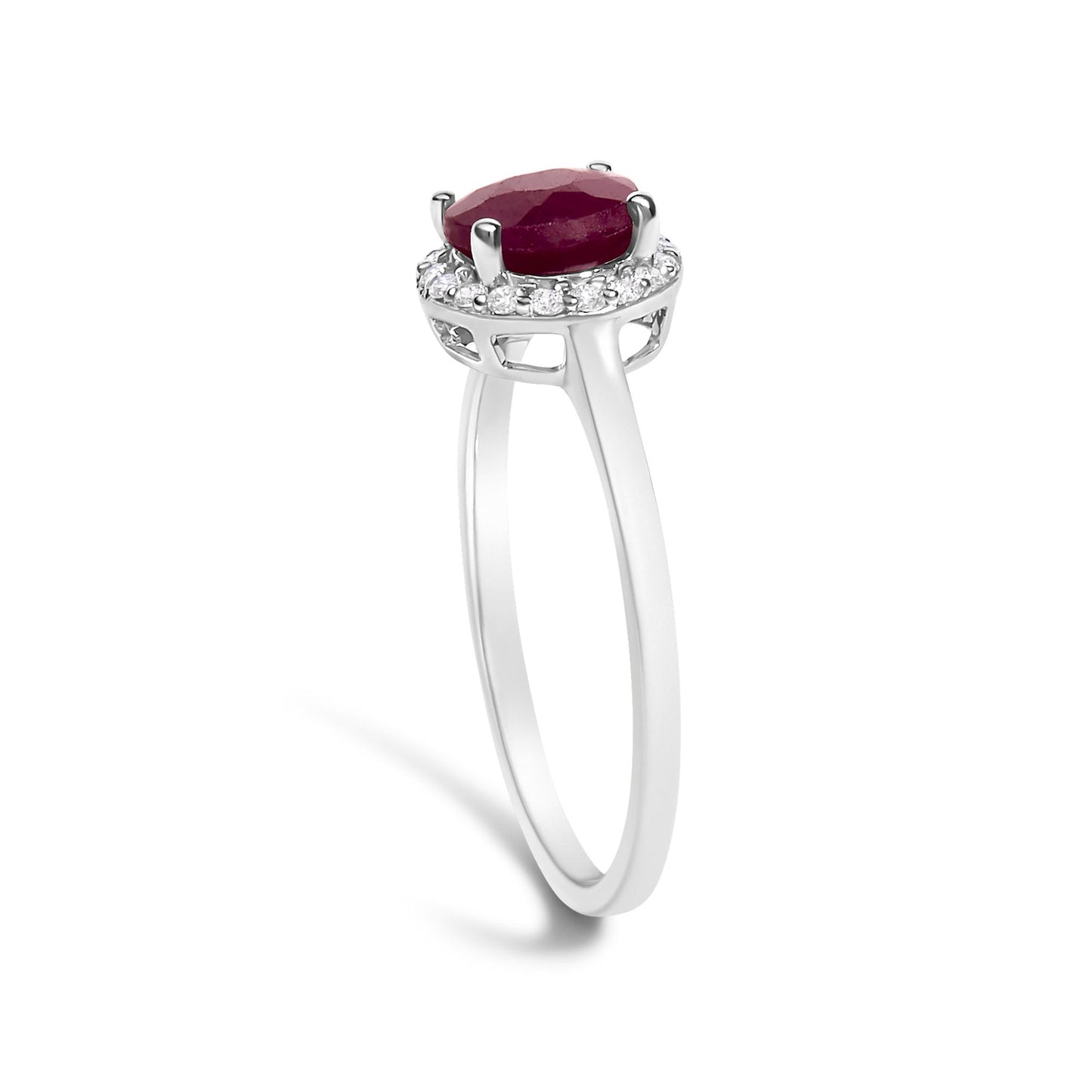White metal ring shown from a side angle with a round red gemstone set in four prongs on top, surrounded by small round white gemstones in a shared prong setting.