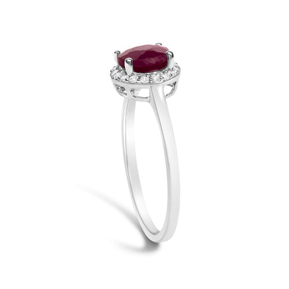 White metal ring shown from a side angle with a round red gemstone set in four prongs on top, surrounded by small round white gemstones in a shared prong setting.