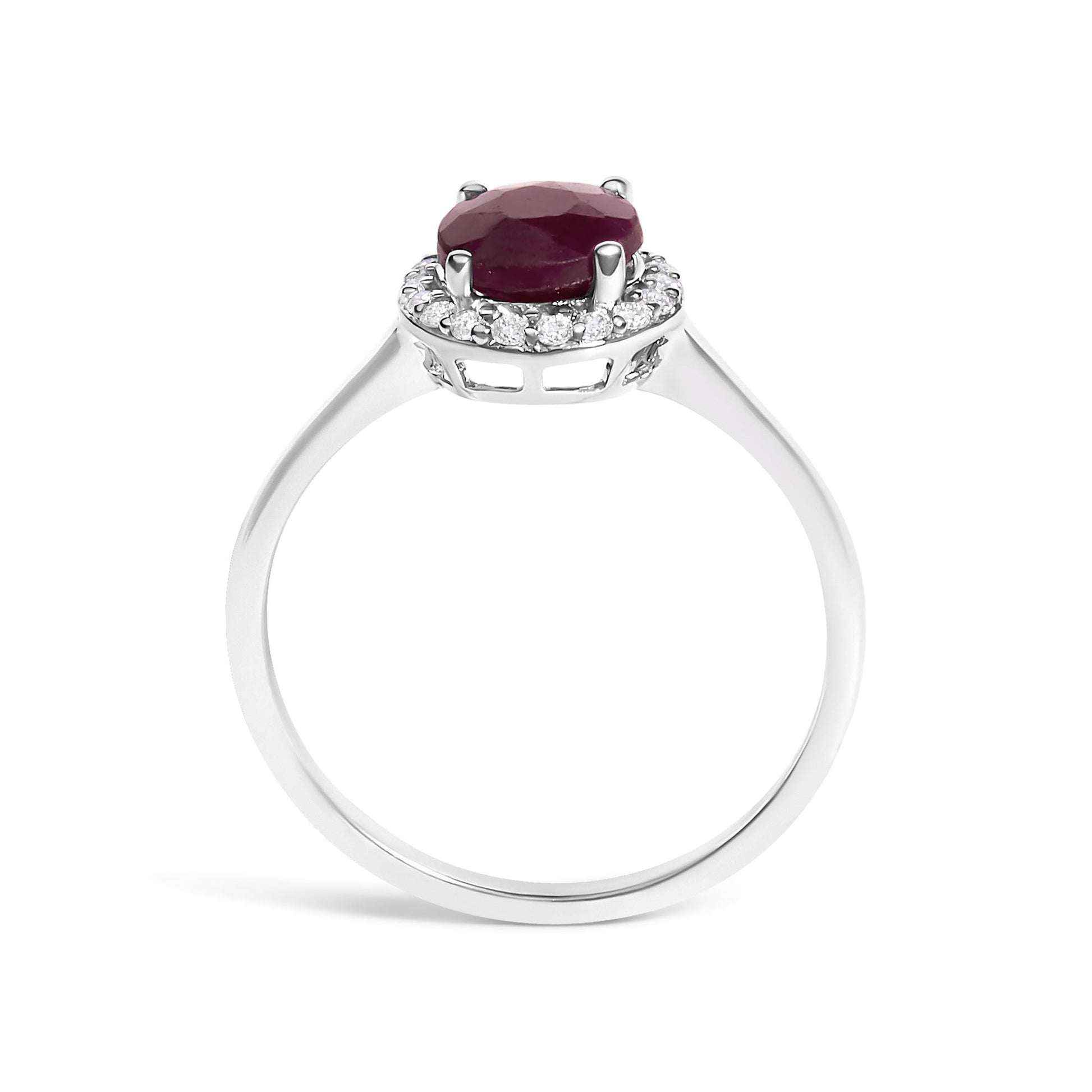 White metal ring shown from the front angle on a white background with a round red gemstone in a four-prong setting, surrounded by small round white gemstones in a shared prong setting.