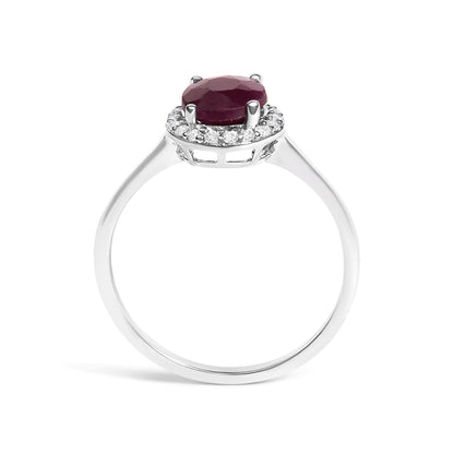 White metal ring shown from the front angle on a white background with a round red gemstone in a four-prong setting, surrounded by small round white gemstones in a shared prong setting.