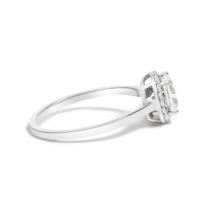 Side view of a white metal ring with a round center white gemstone in a four-prong setting, surrounded by a halo of smaller round white gemstones in shared prong settings. Ring shown against a white background.