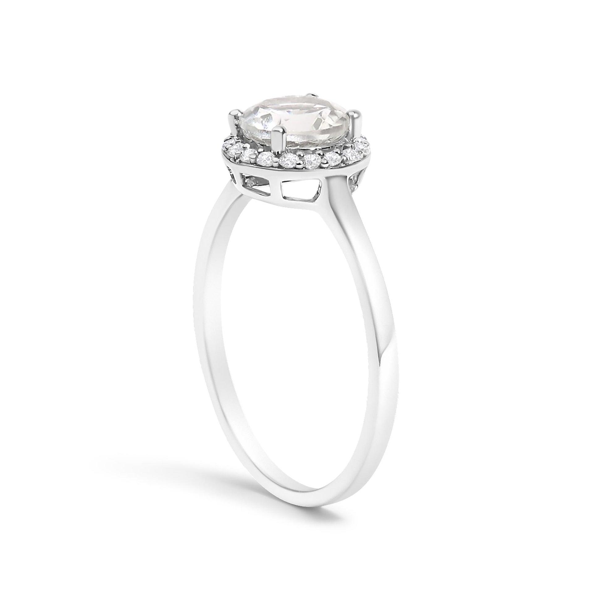 White metal ring with a raised round white gemstone held by four prongs, surrounded by a halo of smaller round white gemstones in shared prong settings, shown from a side angle on a white background.