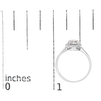 White metal ring with a round white gemstone center set in four prongs, surrounded by a halo of round white gemstones in shared prong setting, shown on a scale from a side angle.