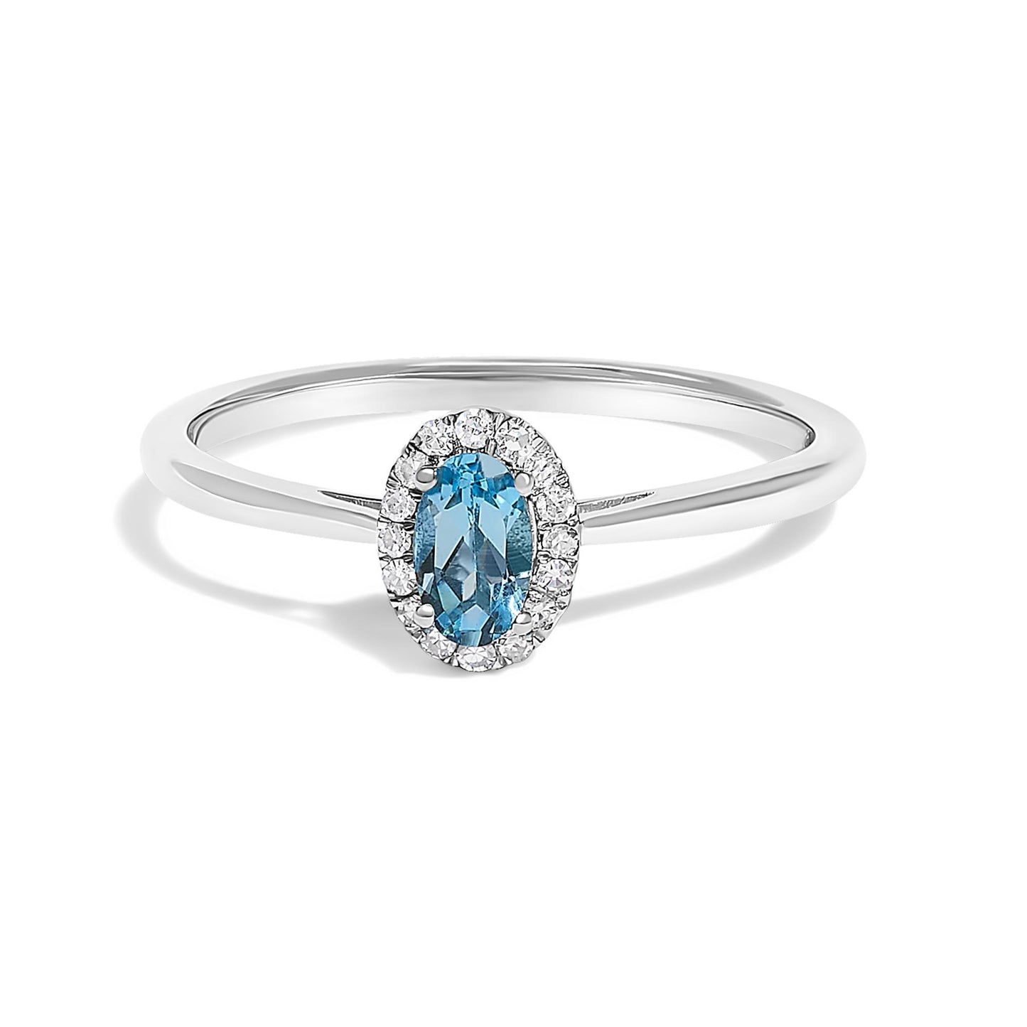 Close-up front angle of a white metal ring with an oval blue gemstone in a prong setting, surrounded by a halo of small white gemstones in a micro-pave setting.