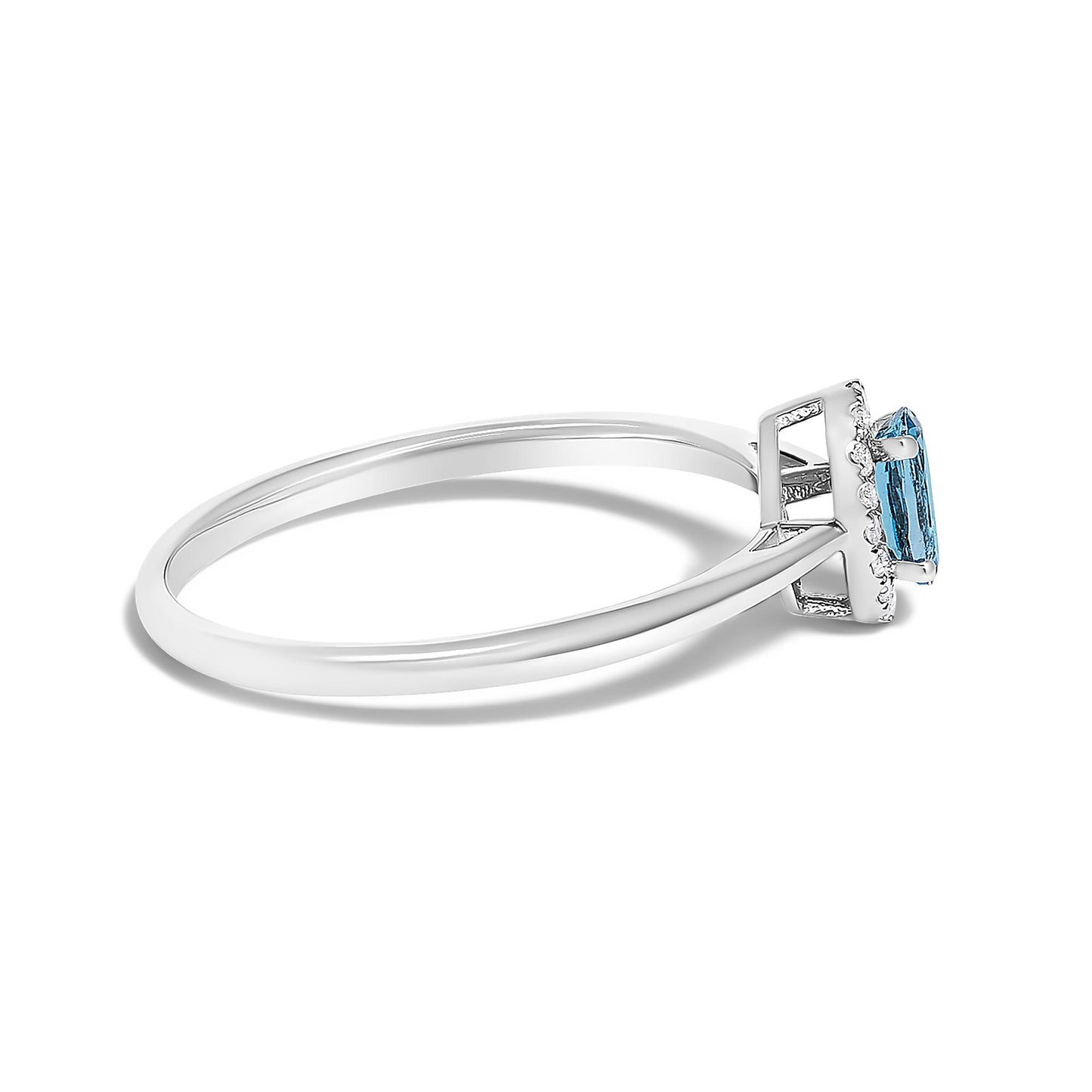 Side angle close-up of a white ring featuring a blue oval gemstone in a prong setting surrounded by small white round gemstones in a micro-pave setting.