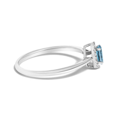 Side angle close-up of a white ring featuring a blue oval gemstone in a prong setting surrounded by small white round gemstones in a micro-pave setting.