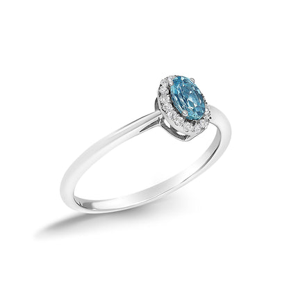 White metal ring shown at an angled close-up, featuring an oval blue gemstone in a prong setting surrounded by a halo of small round white gemstones in a micro-pave setting.