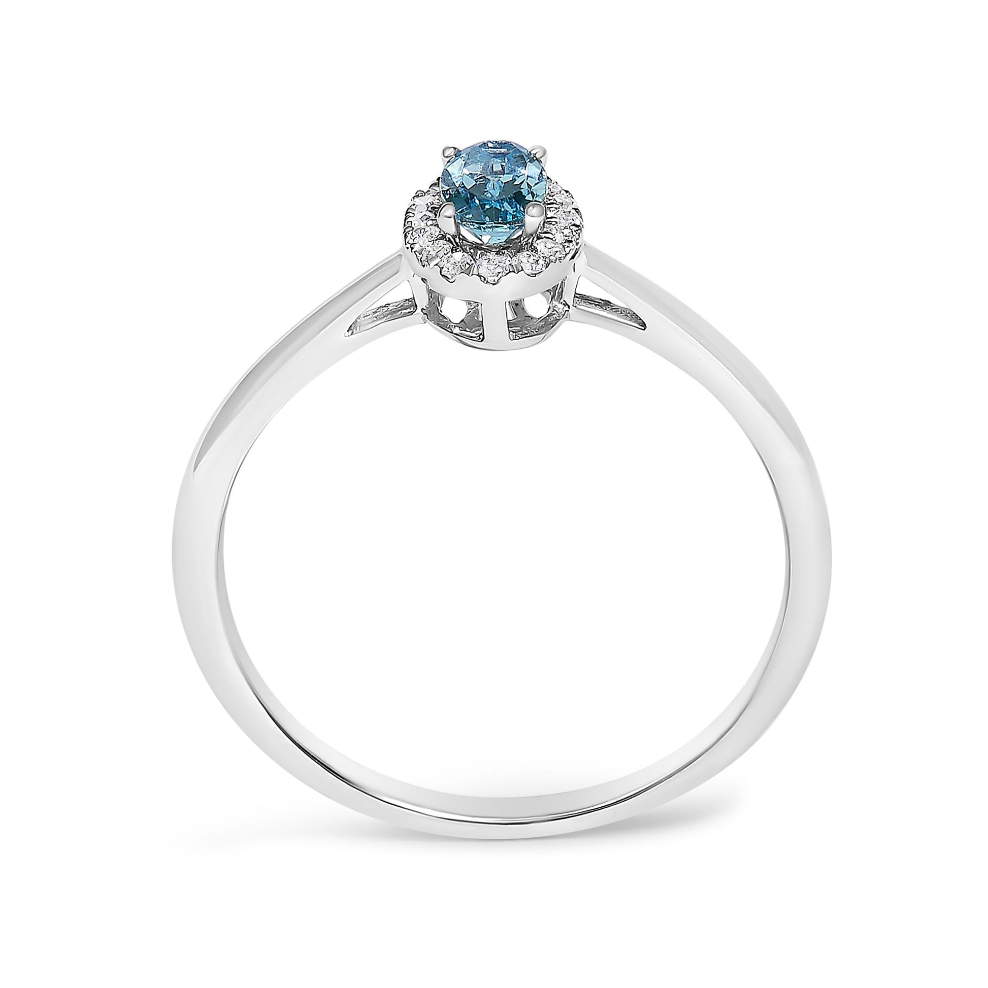 White metal ring with a round blue gemstone in the center, surrounded by small white gemstones in a halo design, shown from a front angled view on a white background.