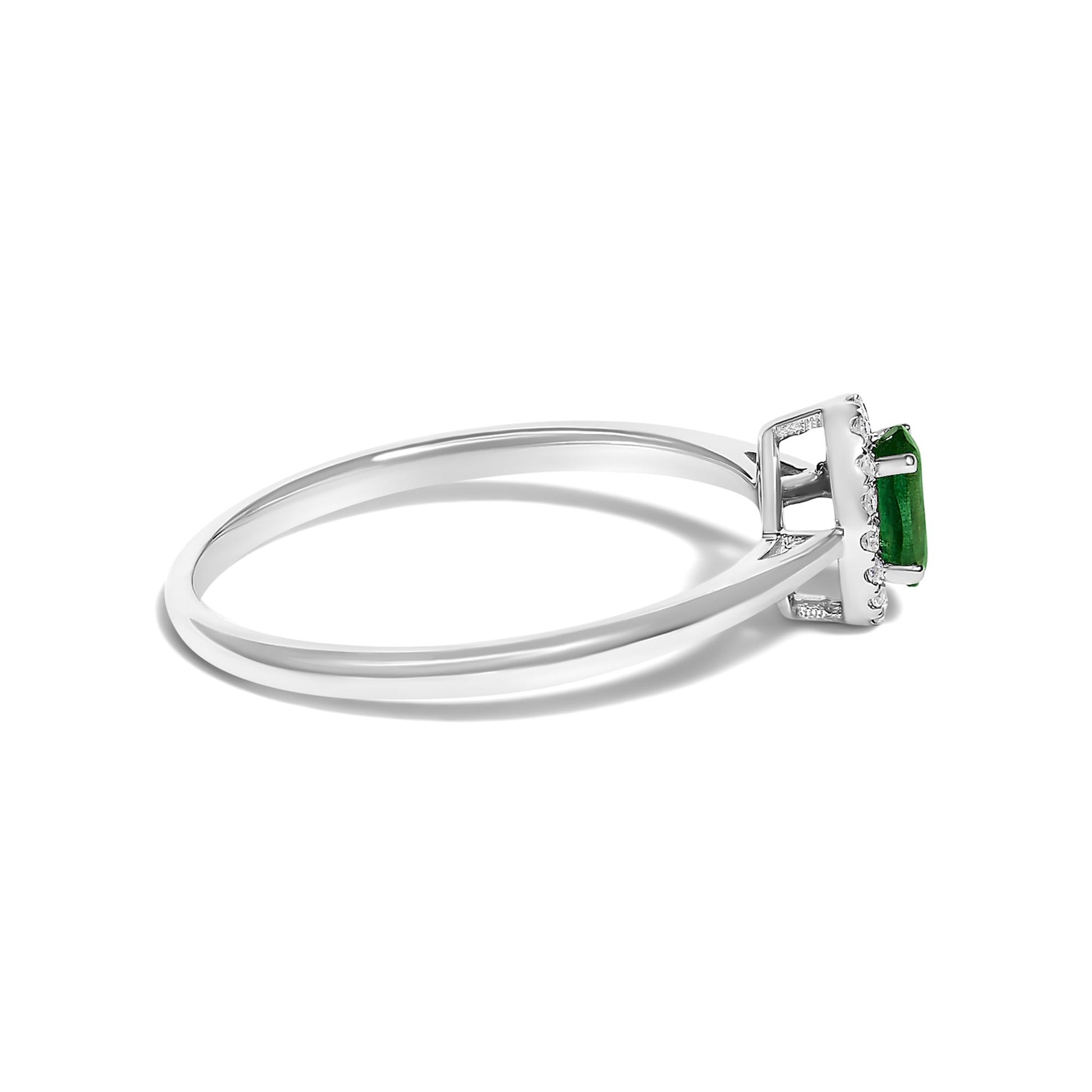 Side view of a white metal ring with an oval green gemstone held by prongs, surrounded by small round white gemstones in a micro-pave setting.
