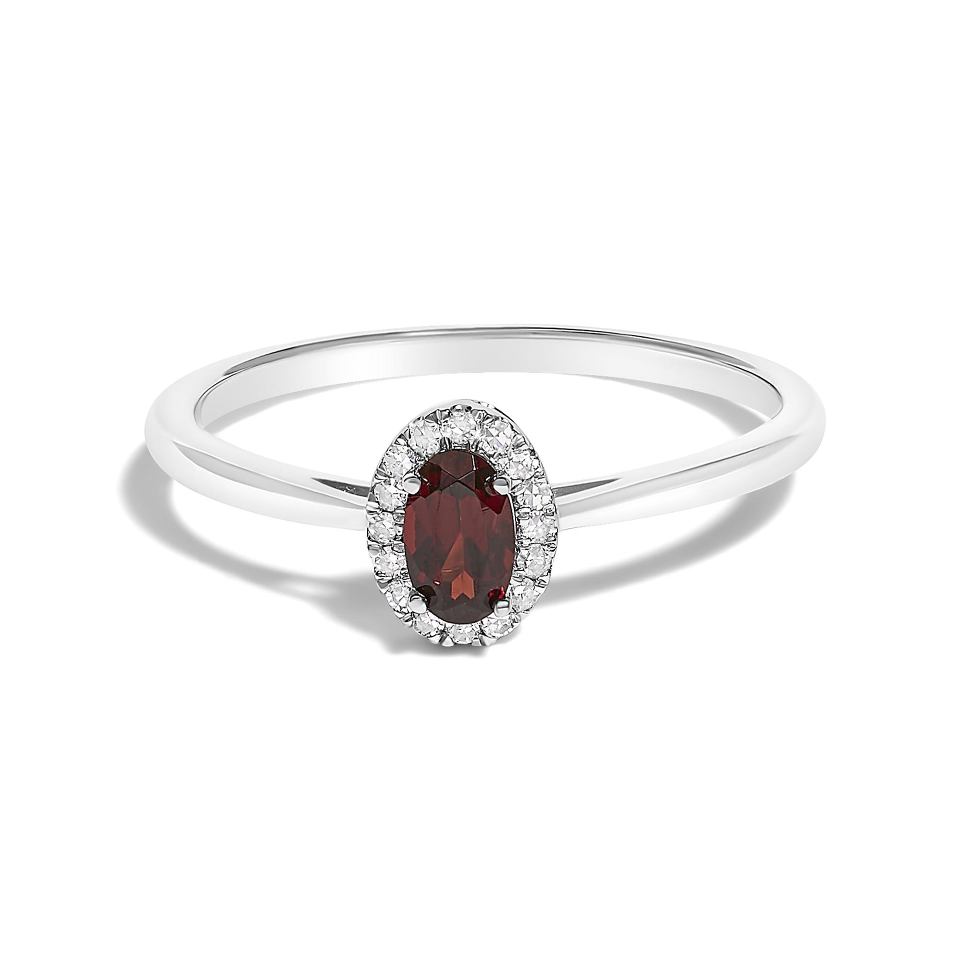 White metal ring with an oval red gemstone in a prong setting surrounded by small white gemstones in a micro-pave setting, shown in a close-up front angle on a white background.