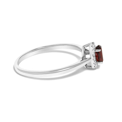 Side view of a white metal ring with a single oval red gemstone in prong setting and surrounded by small round white gemstones in a micro-pave setting.
