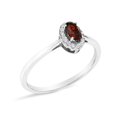 White metal ring with an oval red gemstone in a prong setting, surrounded by a micro-pave setting of small round white gemstones, shown in a close-up angled view.